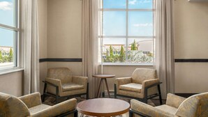 A room with a large window, two armchairs, a small round table, and a sofa. - Hampton Inn & Suites Exeter (Exeter)
