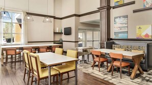 A restaurant with multiple dining tables and chairs, a bar area, and artwork on the walls. - Hampton Inn & Suites Exeter (Exeter)