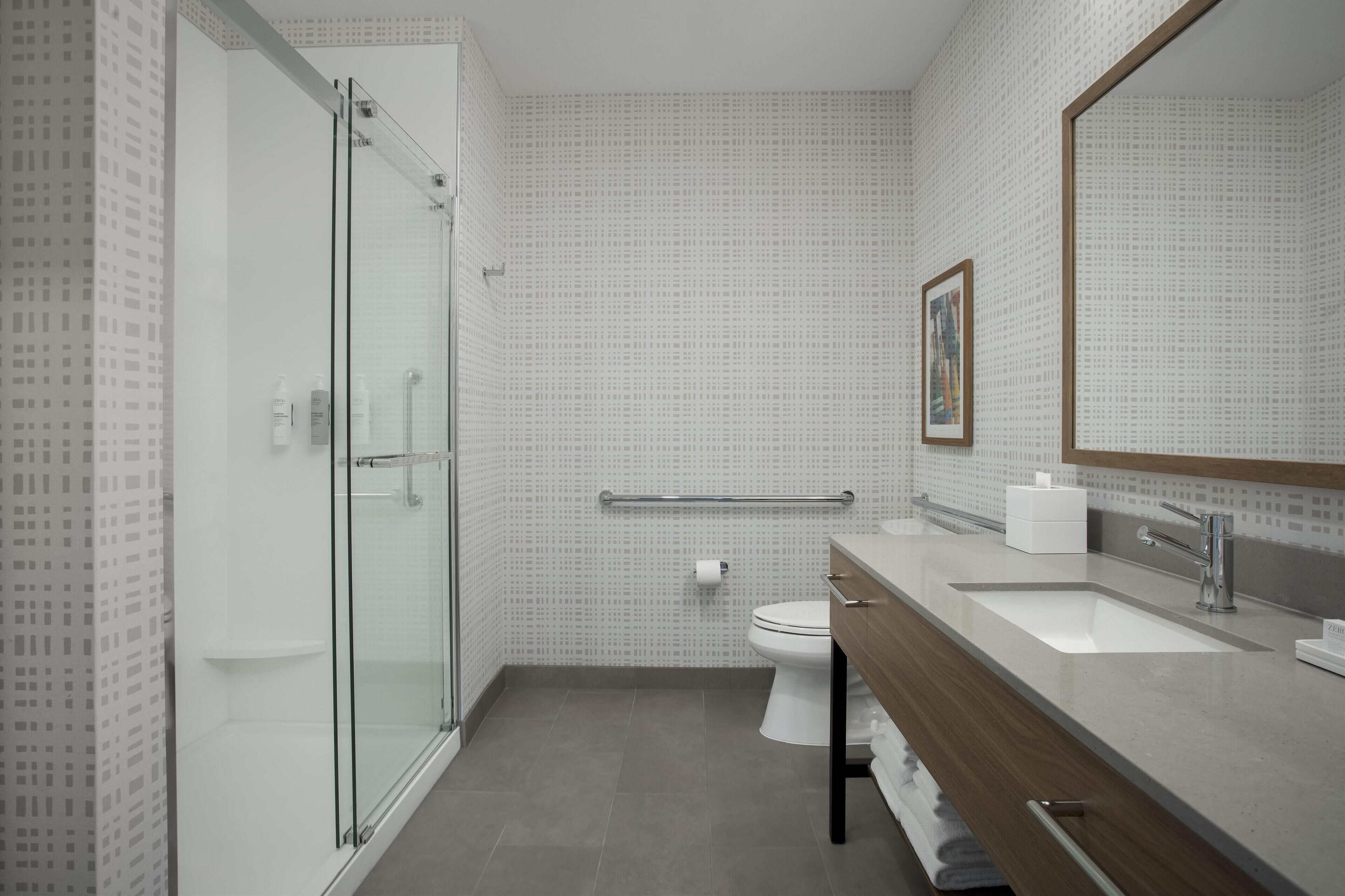 Une salle de bain moderne avec une douche à parois de verre, des toilettes blanches et un meuble-lavabo avec un miroir.