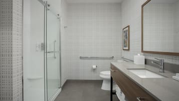 Une salle de bain moderne avec une douche à parois de verre, des toilettes blanches et un meuble-lavabo avec un miroir.