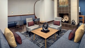 A modern living room with a sofa, armchairs, a coffee table, and a fireplace. - Hyatt Place Houston/Sugar Land (Sugar Land)