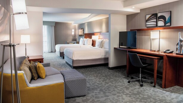 Una habitación de hotel con cama, escritorio, silla, sofá y televisor.