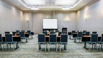A conference room with rows of chairs, a large screen, and a podium.