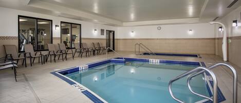 A swimming pool with a tiled deck, a changing room, and a seating area with chairs.
