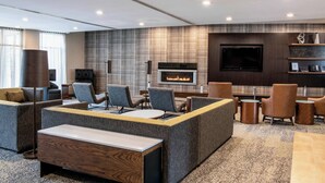 A modern lounge area with sofas, a fireplace, a flat-screen TV, and a coffee table. - Courtyard by Marriott Edmonton West (Edmonton)