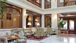 Un hall espacioso con techo alto, muebles de madera ornamentados y una imponente escalera.