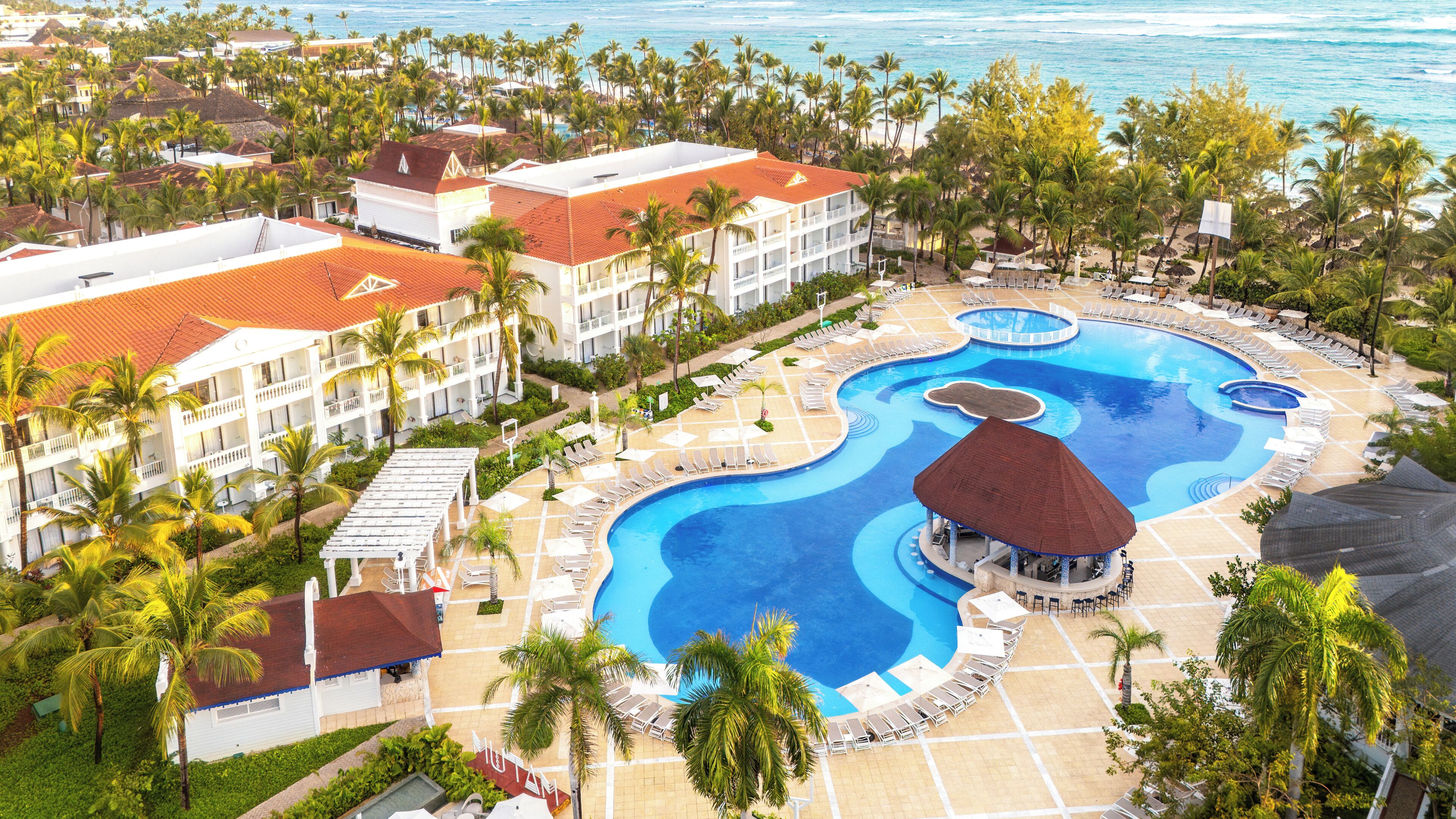Un resort con una grande piscina, palme e vista sull'oceano.