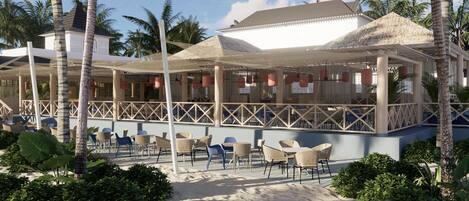 Un restaurant situé en bord de mer, avec une terrasse, des palmiers et un espace abrité avec des parasols.