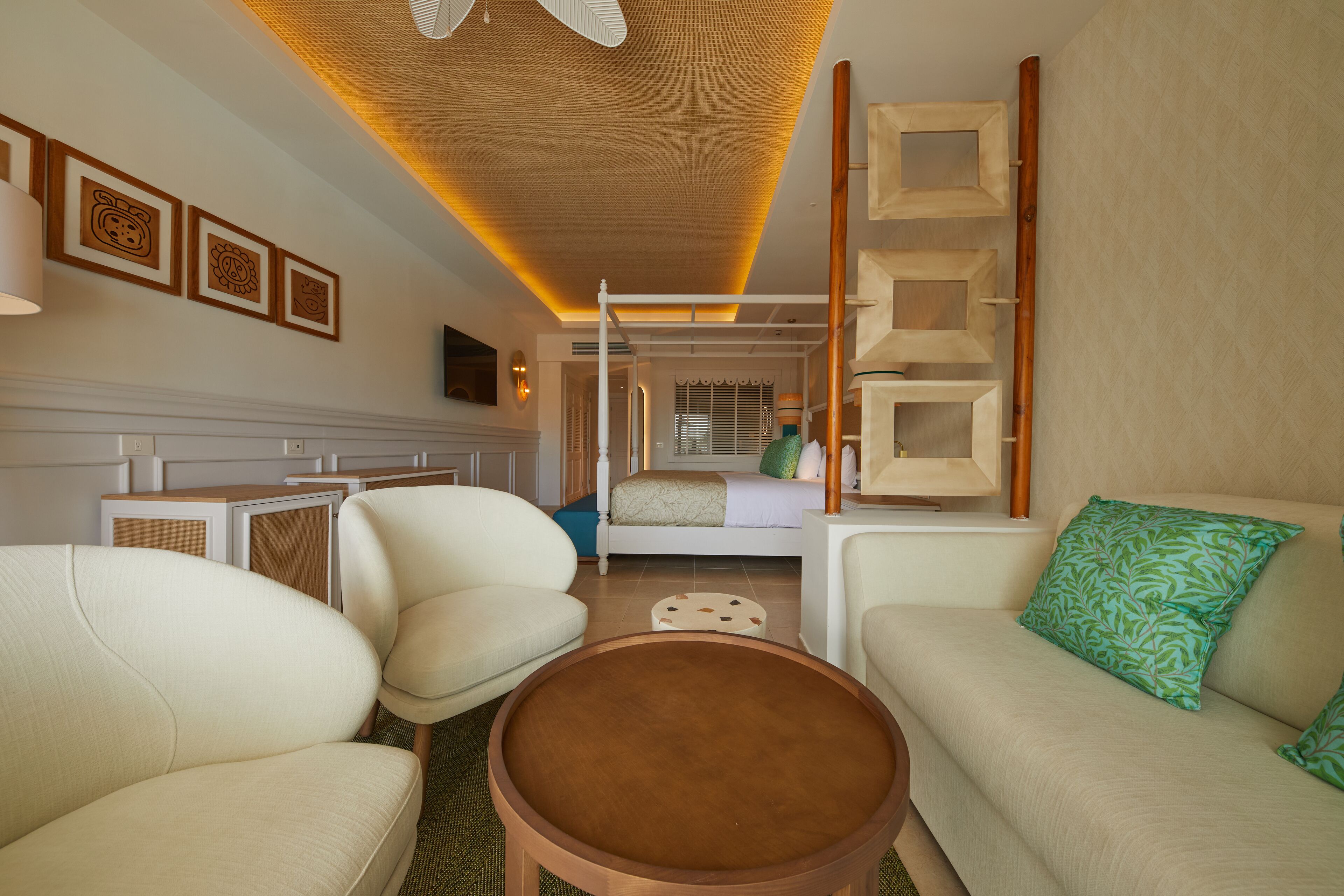Una habitación de hotel moderna con una cama, dos sofás, una mesa de centro y un televisor.