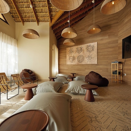 A room with a wooden ceiling, woven light fixtures, a large TV, and a patterned floor.