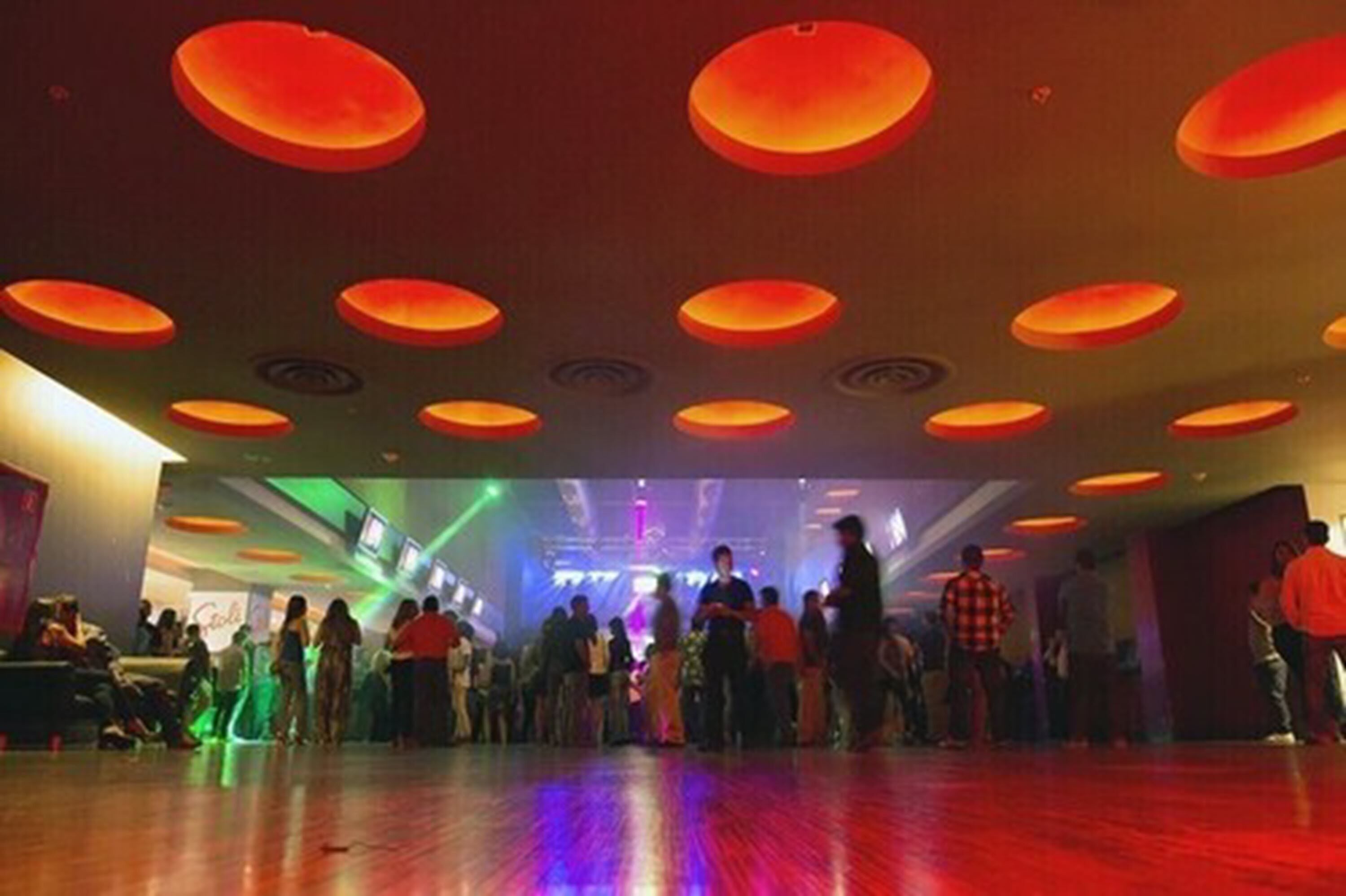 A spacious dance floor with a wooden floor and a ceiling with circular light fixtures.