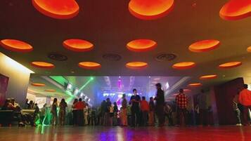 A spacious dance floor with a wooden floor and a ceiling with circular light fixtures.