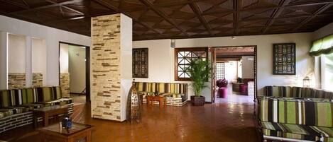 A spacious lobby with a high ceiling, a stone pillar, and a seating area with striped sofas and tables.