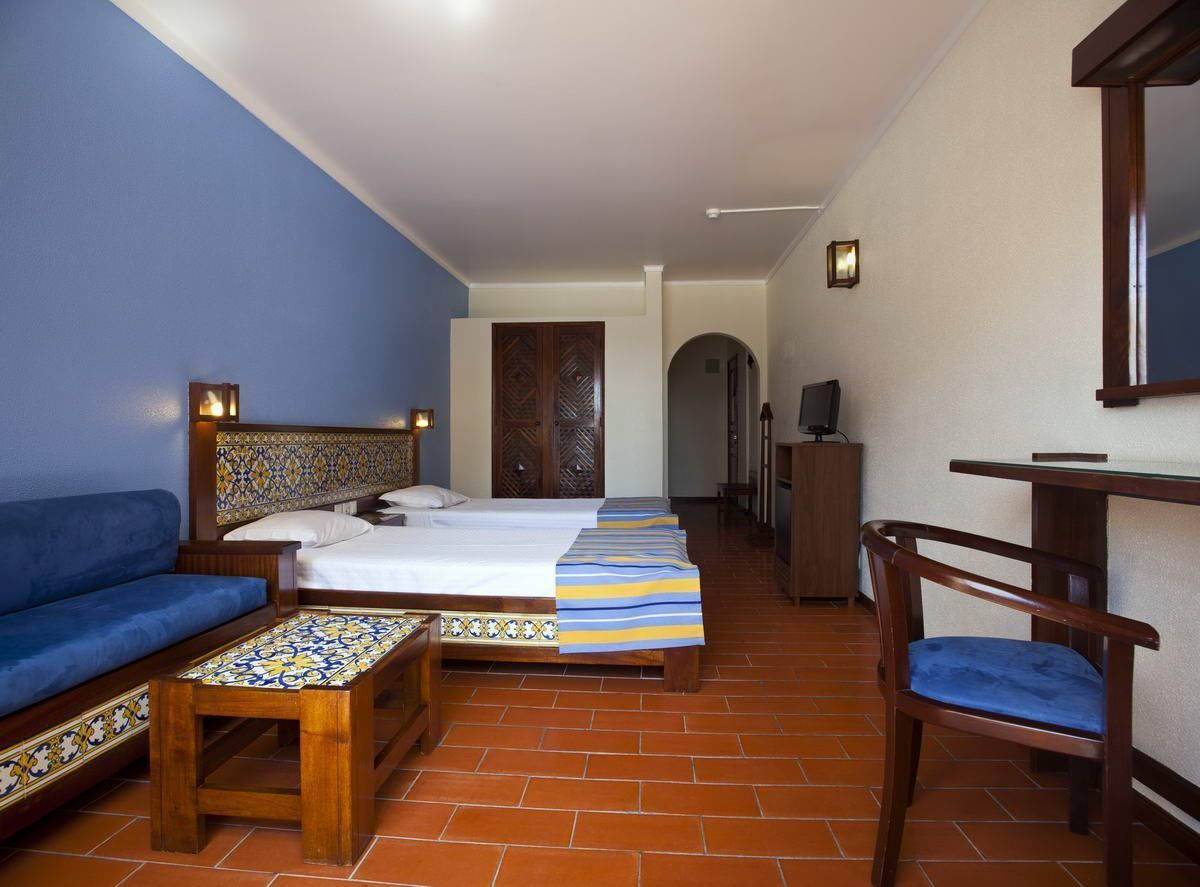 Ein Hotelzimmer mit Bett, Sofa, Sessel, kleinem Tisch und Fernseher.