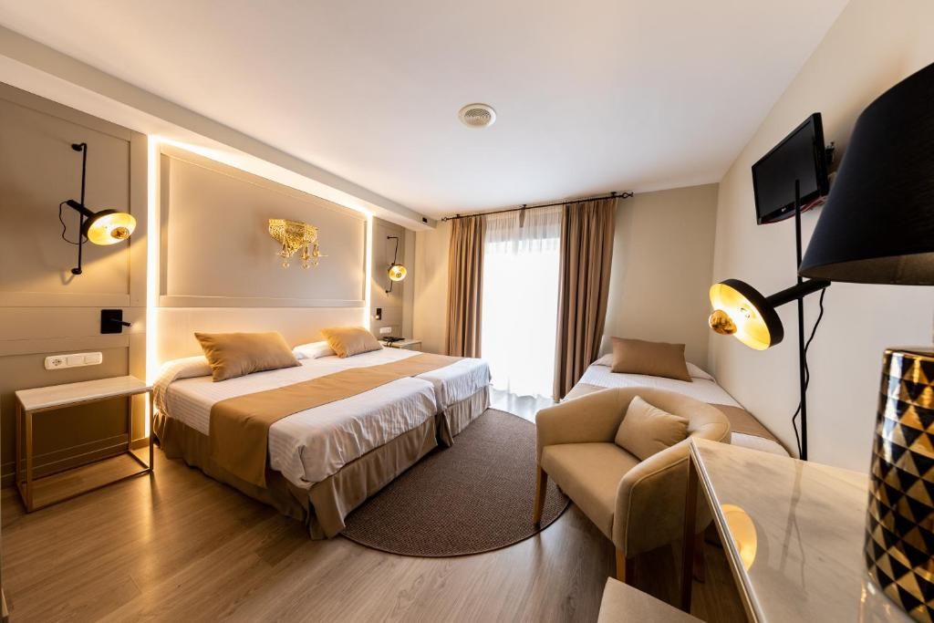 A hotel room with a large bed, a sofa, a desk, and a TV.