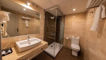 Un baño moderno con ducha de vidrio, lavamanos con espejo y retrete.