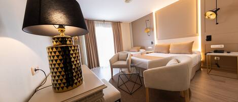 A hotel room with a desk, a lamp, a bed, and a chair.
