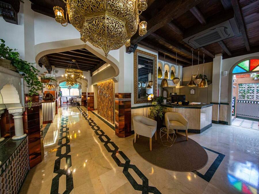 Un vestíbulo de hotel con suelo de mármol, candelabros ornamentados y un mostrador de recepción.