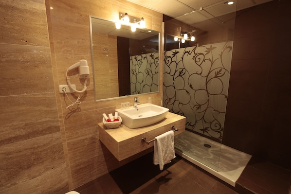 A modern bathroom with a large mirror, a sink, a hairdryer, and a shower. - Hotel Casablanca (Almunecar)