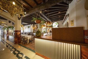 A restaurant with a wooden ceiling, hanging plants, and a tiled floor.