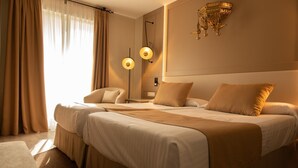 A hotel room with a large bed, two bedside tables, a chair, and a decorative wall lamp. - Hotel Casablanca (Almunecar)