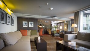 A modern hotel lobby with a sofa, armchairs, a coffee table, and a staircase leading to an upper level. - Altera Hotel im Herbartgang (Oldenburg)