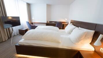 Een hotelkamer met een groot bed, een bureau, een stoel, een televisie en een lamp.