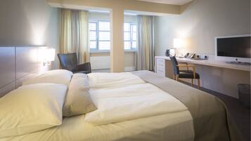 A hotel room with a large bed, a desk with a computer, and a TV.