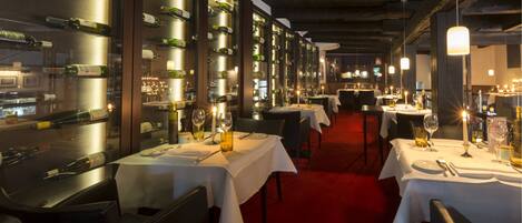 Un restaurant doté de nombreuses tables, chacune étant dressée avec une nappe blanche, des verres à vin et des bouteilles.