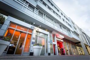 Um hotel com fachada moderna, exibindo uma placa grande com a palavra 'Hotel' e uma placa 'Hertta'.