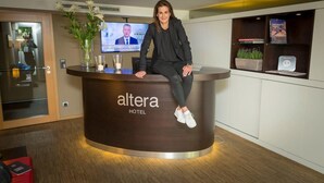 A reception desk at the Altera Hotel with a modern design, a television screen, and a vase with flowers. - Altera Hotel im Herbartgang (Oldenburg)