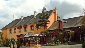 A traditional building with a sloped roof, a covered porch, and a small garden area in front. - Hotel Le Clos Champel (Cesson-Sevigne)
