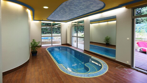 An indoor swimming pool with a wooden floor, large windows, and a ceiling with a cloud pattern. - Hotel Le Clos Champel (Cesson-Sevigne)