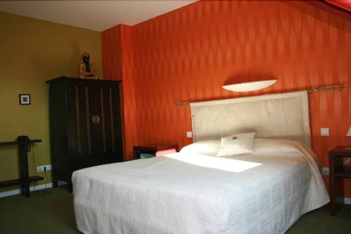 Ein Schlafzimmer mit einem Bett, einem Nachttisch, einer Kommode und einer Wandlampe.