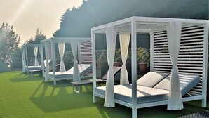 A row of white outdoor seating areas with canopies, each with a cushioned bench and a small table. - Andris Hotel (Ercolano)