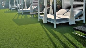 A row of white outdoor seating areas with canopies, each with a cushioned bench and a small table.
