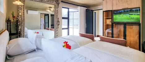 A hotel room with two beds, a large mirror, a television, and a view of a sports field.