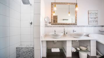 A modern bathroom with a shower, two sinks, a vanity, and a mirror with a decorative frame.
