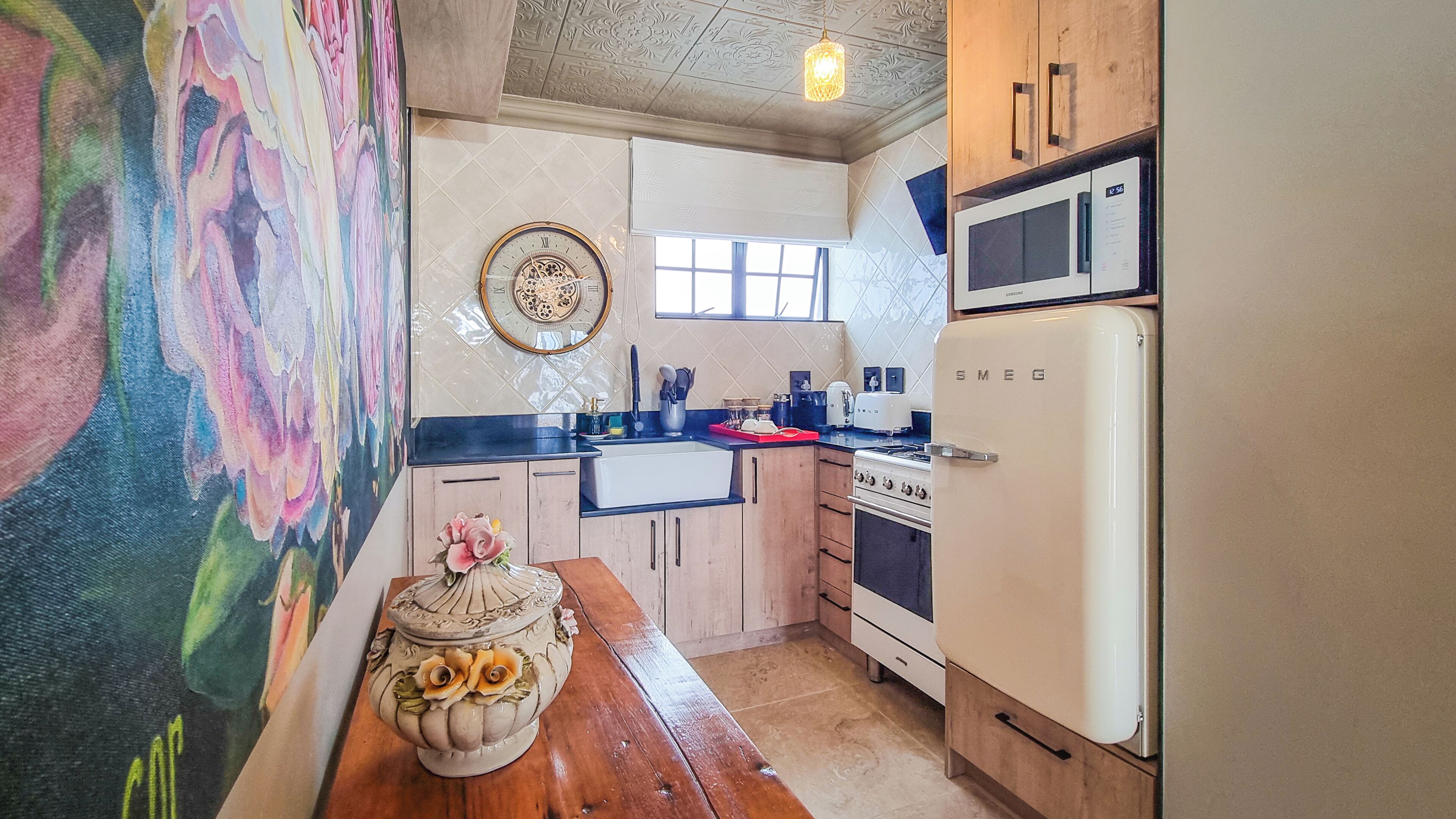 A kitchen with wooden cabinets, a vintage microwave, a stove, and a decorative vase on the counter.