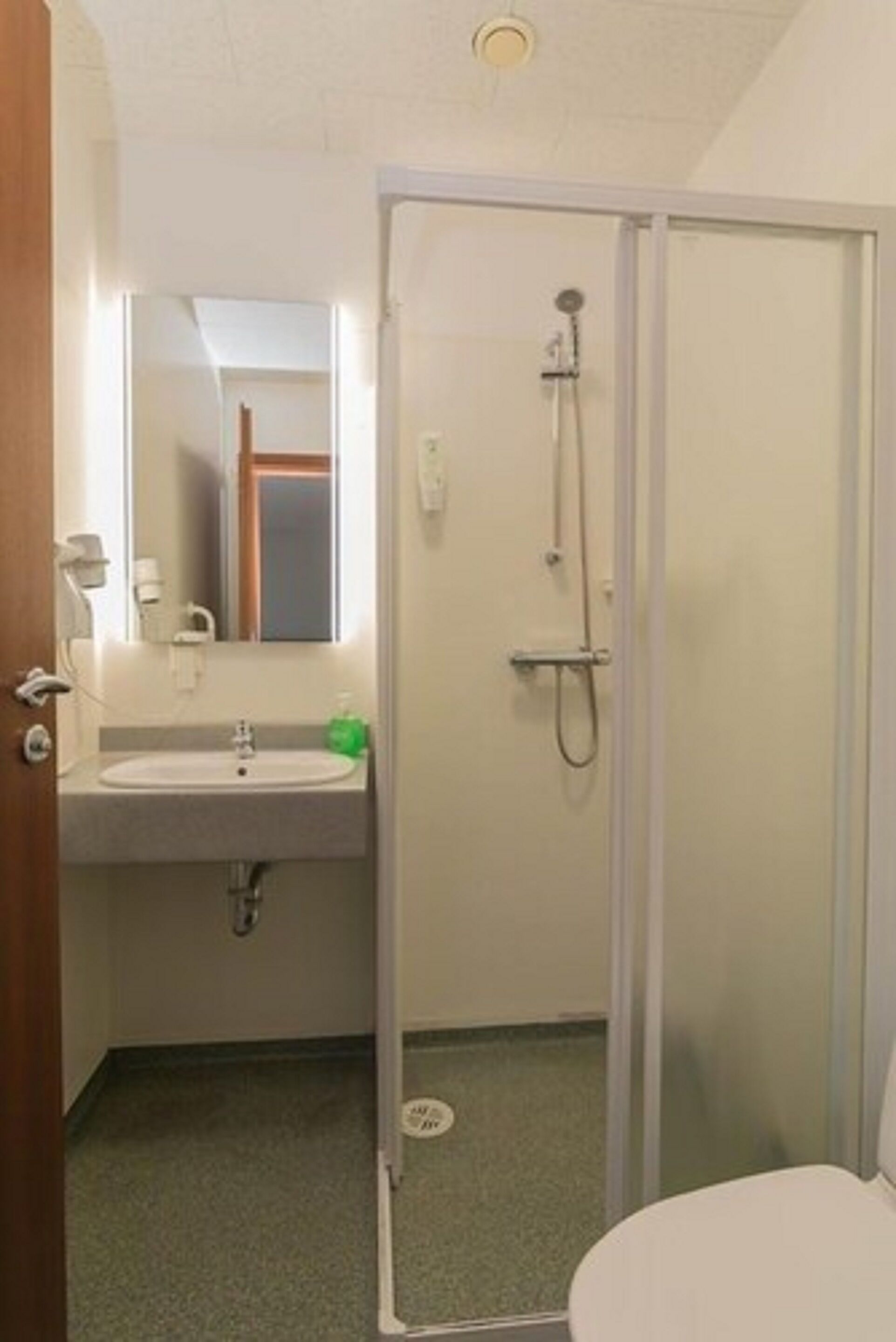 Un baño con lavamanos, espejo, ducha e inodoro.