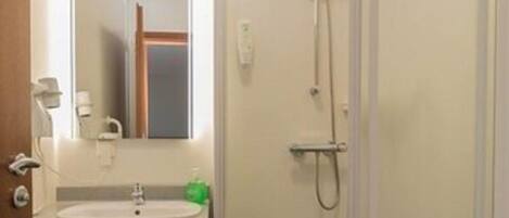 Un baño con lavamanos, espejo, ducha e inodoro.