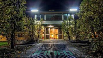 A hotel entrance at night with a well-lit facade and a visible sign.