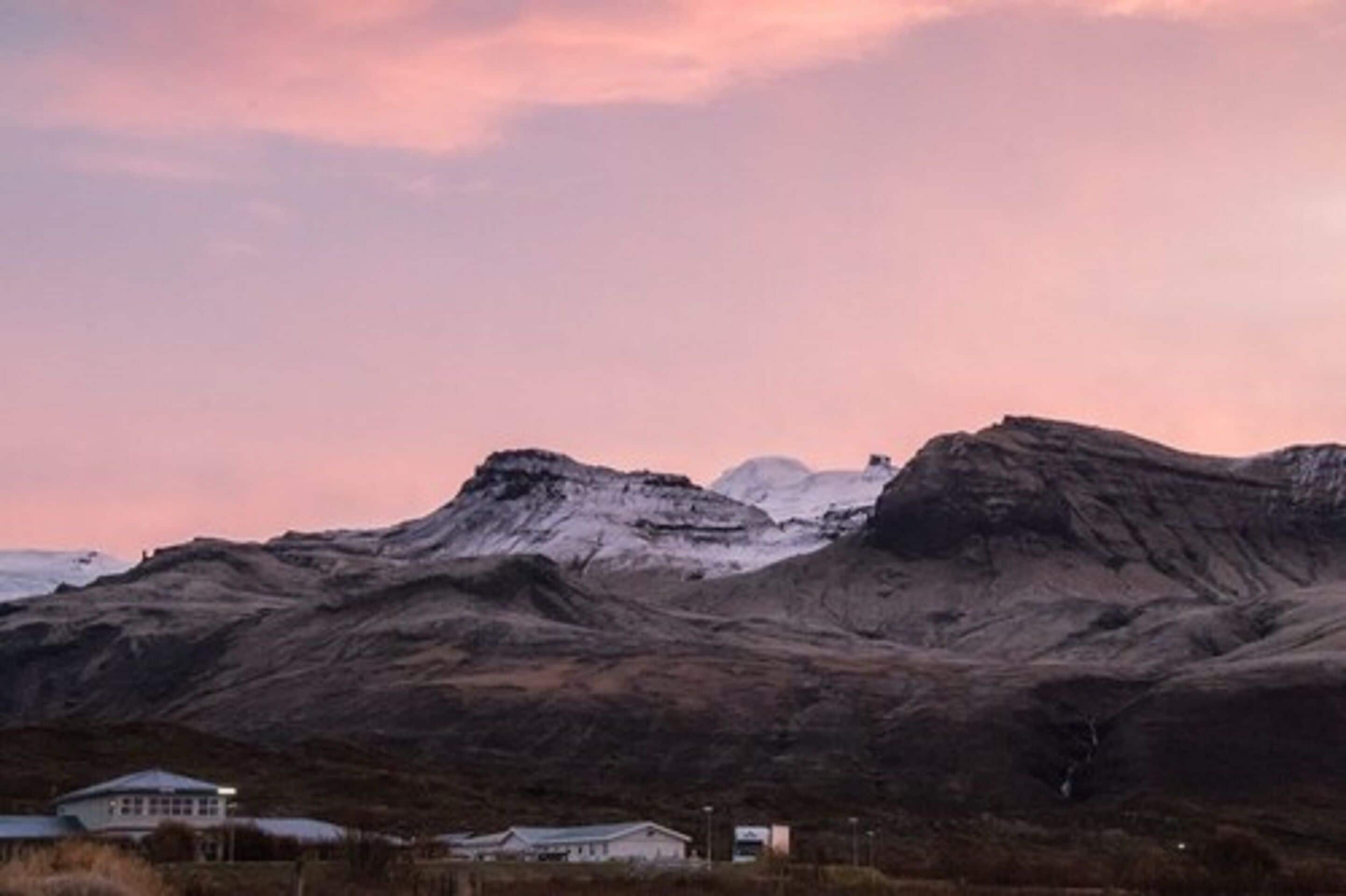 A mountainous landscape with a house in the foreground.