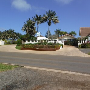 Zona residencial con valla blanca, palmeras y cielo despejado.