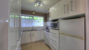 A kitchen with white cabinets, a microwave, and a refrigerator. - Shiralee Executive Cottages (Norfolk Island)