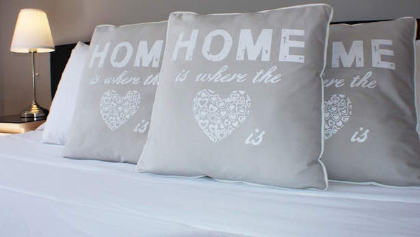A bed with three pillows that read "HOME is where the heart is." - Dear Porto Guest House (Porto)