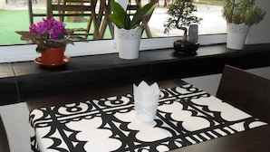 A table with a black and white patterned tablecloth, a white decorative item, and potted plants on a windowsill. - Dear Porto Guest House (Porto)