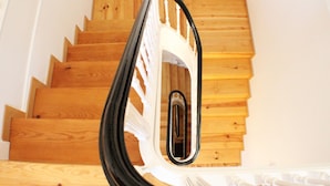 A wooden staircase with a white railing and a black object on the lower step. - Dear Porto Guest House (Porto)