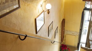 A staircase with a handrail, a wall with framed pictures, and a light fixture.