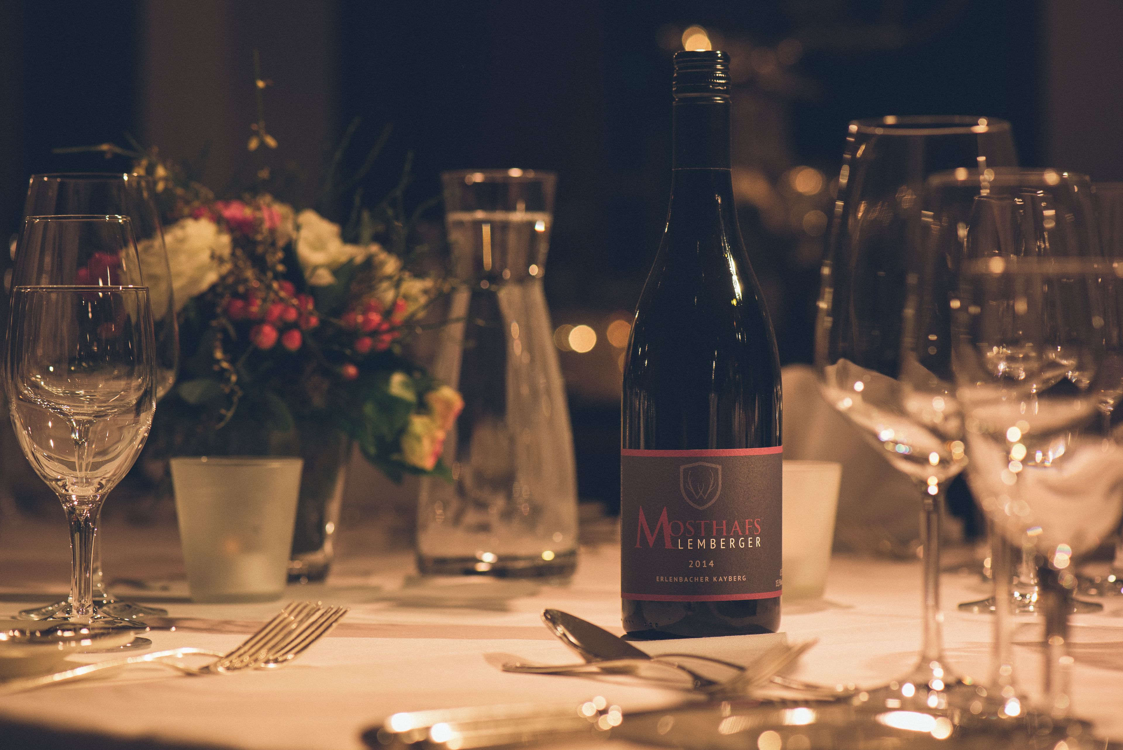 Una mesa dispuesta con copas de vino, una botella y cubiertos.